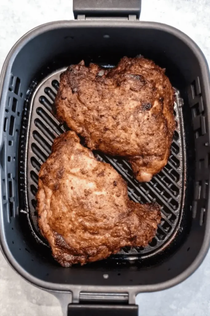 Air Fryer Steak 4 Air Fryer Steak cooking inside the basket, showing seared ribeyes in progress